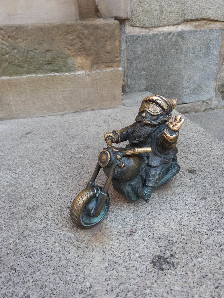 Krasnal Wentyl na motocyklu przy kamiennej ścianie