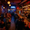 wnętrze popularnego baru we Wrocławiu z pełną salą gości, neonami, drinkami i barmanami za ladą – klimat nocnego życia miasta