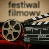 Zbliżenie na klasyczną taśmę filmową i klaps reżyserski na tle czerwonych foteli kinowych – scena festiwalu filmowego we Wrocławiu