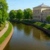 spacerowicze nad Fosą Miejską we Wrocławiu w otoczeniu zieleni i zabytkowych budynków