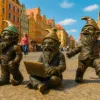 Trzy krasnale we Wrocławiu na tle kolorowych kamienic i nieba, w zabawnych pozach, w centrum miasta.