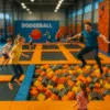 Tilt-shift zdjęcie: park trampolin we Wrocławiu z basenem z gąbkami, dziećmi i dorosłymi skaczącymi na trampolinach, strefą dodgeball i ścianką wspinaczkową w tle – perspektywa miniaturowa