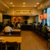 wnętrze restauracji ramen we Wrocławiu z drewnianymi stołami, czerwonymi lampionami i gośćmi jedzącymi przy barze – klimat japońskiej kuchni w centrum miasta
