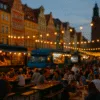 Wieczorny street food market we Wrocławiu z food truckami i ludźmi przy stolikach na tle kolorowych kamienic