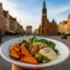Wegański talerz z batatami, brukselką, kaszą i hummusem na tle Rynku we Wrocławiu – ilustracja stylu życia roślinnego w centrum miasta.