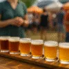 Zestaw degustacyjny piw kraftowych na festiwalu plenerowym z rozmytym tłem pełnym uczestników i namiotów wystawców