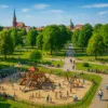 Plac zabaw w zielonym parku we Wrocławiu – dzieci bawią się na zjeżdżalniach, rodziny spacerują i odpoczywają latem na trawie