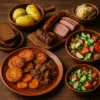 Tradycyjne estońskie dania na drewnianym stole: ziemniaki, ciemny chleb, kiełbasa, gulasz, surówki i kiszonki w glinianych miskach