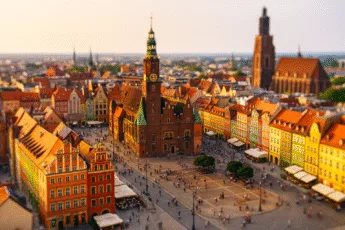 Zachód słońca nad wrocławskim Rynkiem z Ratuszem, tłumami turystów i kolorowymi kamienicami – idealna pora na wizytę