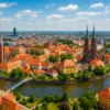 Ostrów Tumski we Wrocławiu w czerwcu – panorama miasta nad Odrą z czerwonymi dachami i zielenią