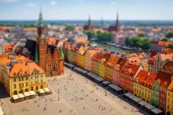 letni Rynek we Wrocławiu z kolorowymi kamienicami i ruchem turystycznym na tle Odry i kościołów