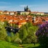 Piękny widok na Pragę w słoneczny dzień z Mostem Karola i rzeką Wełtawą, typowy obraz czeskiej architektury z historycznymi budynkami, idealny na majówkę w Czechach