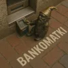 Bankomatki – wrocławski krasnal przy miniaturowym bankomacie, z napisem BANKOMATKI wpisanym w bruk obok prawdziwego bankomatu