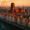 Widok Gdańska z czerwonymi dachami i ceglaną zabudową w stylu industrialnym, z panoramą miasta i stocznią w tle