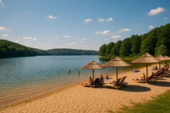Letni krajobraz nad jeziorem w Czechach – plaża, woda, parasole i zielone wzgórza w tle