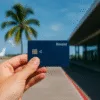 Revolut card held in the hand against the background of the airport and palm - payments abroad on the go