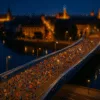 nocny bieg przez most podczas półmaratonu, setki biegaczy w kolorowych strojach na tle iluminowanego miasta i odbicia świateł w rzece