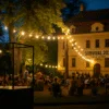 Wieczorna scena festiwalu SURVIVAL przy Zamku Leśnickim – instalacja artystyczna, ludzie na leżakach i światła wśród drzew