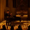 Koncert muzyki klasycznej w gotyckiej katedrze w blasku świec, skrzypek i pianista na tle ołtarza
