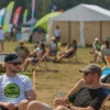Uczestnicy festiwalu na leżakach podczas letniego wydarzenia plenerowego we Wrocławiu, z kolorowymi flagami i namiotami w tle
