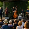 Jazzowy koncert plenerowy w parku podczas Wroclove Jazz Days 2025 – muzycy na scenie, publiczność siedząca, ciepłe światło zachodzącego słońca