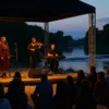 Plenerowy koncert o zmierzchu nad rzeką we Wrocławiu – zespół występuje na scenie przy plaży, w tle widać jaz wodny i most na Odrze