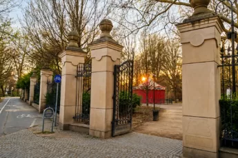 Wejście do Parku Staromiejskiego (Parku Mikołaja Kopernika) we Wrocławiu o zachodzie słońca, ozdobna brama i kamienne filary