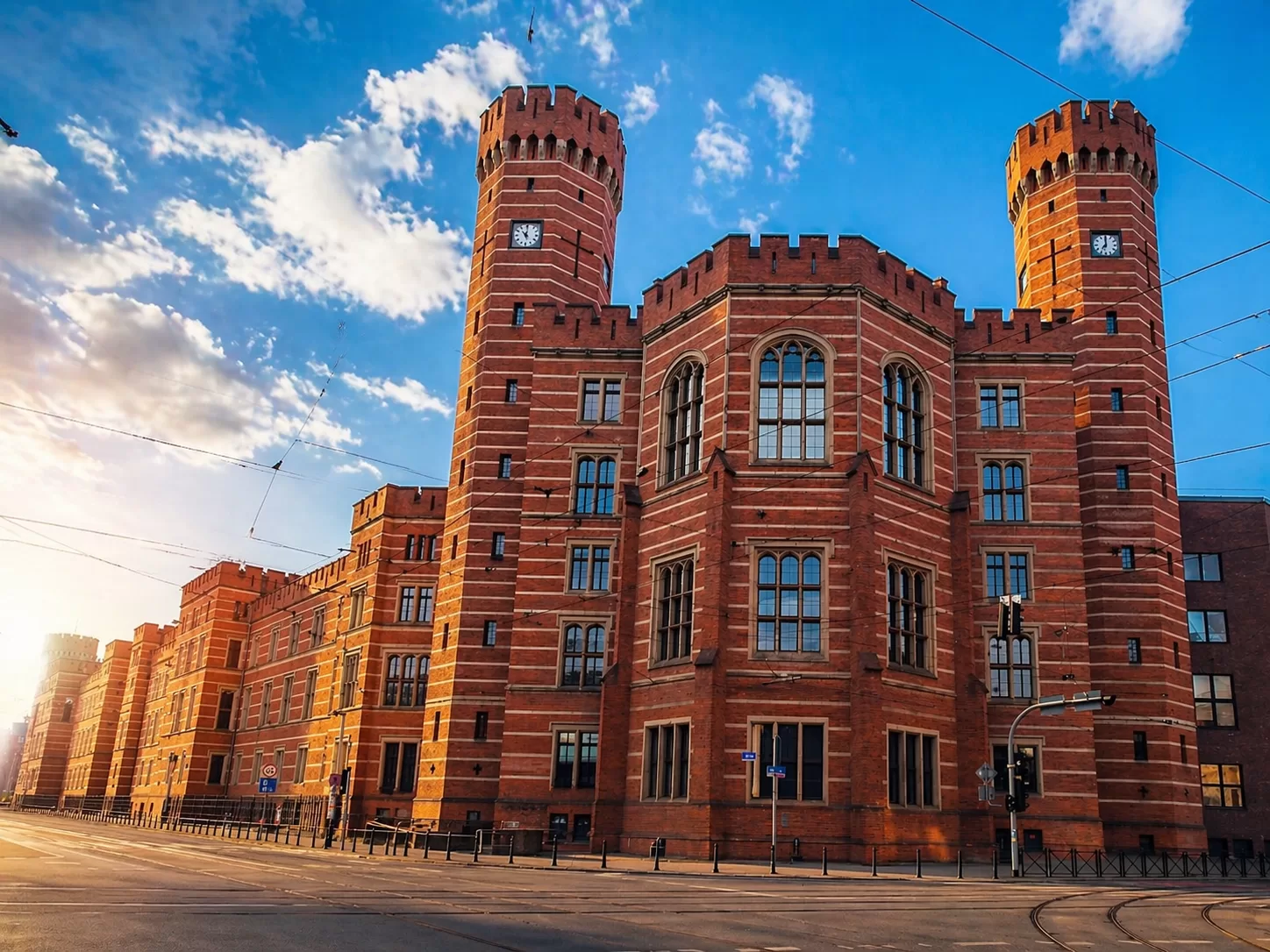 Sąd Okręgowy we Wrocławiu w słoneczny dzień z charakterystyczną ceglaną fasadą i wieżami