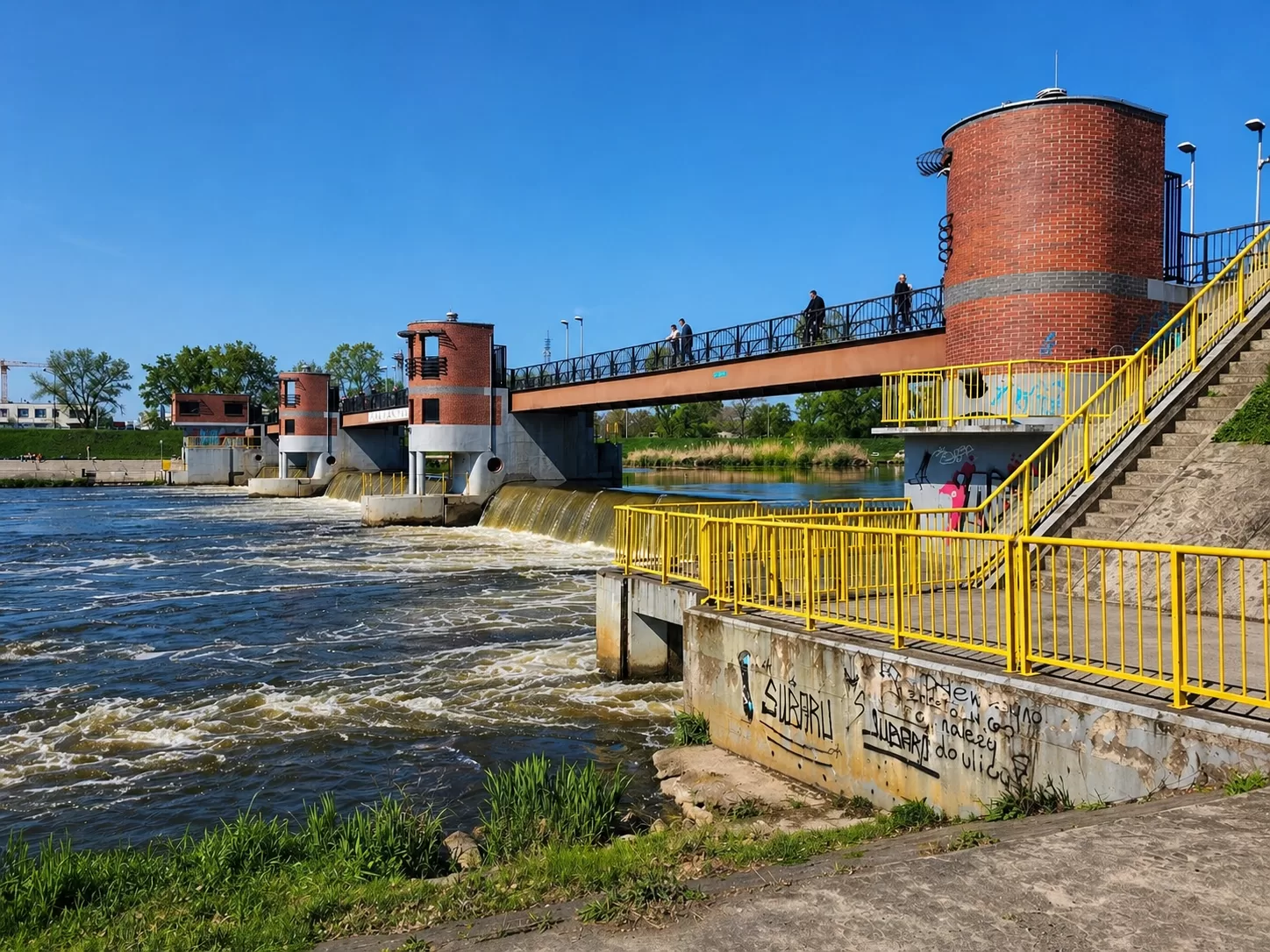 Jaz Opatowicki in Wrocław on the Odra River, a weir with a pedestrian bridge and brick towers