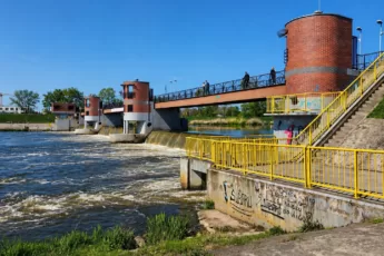 Jaz Opatowicki in Wrocław an der Oder, ein Wehr mit Fußgängerbrücke und Backsteintürmen